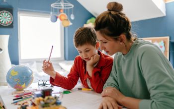 Photo of a young boy being homeschooled by his mother in his bedroom